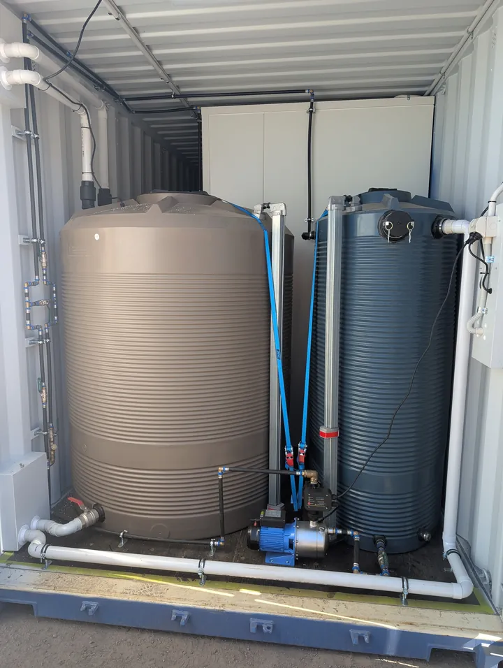 Water tanks and pump plumbed into a container to service a self-contained ablution block